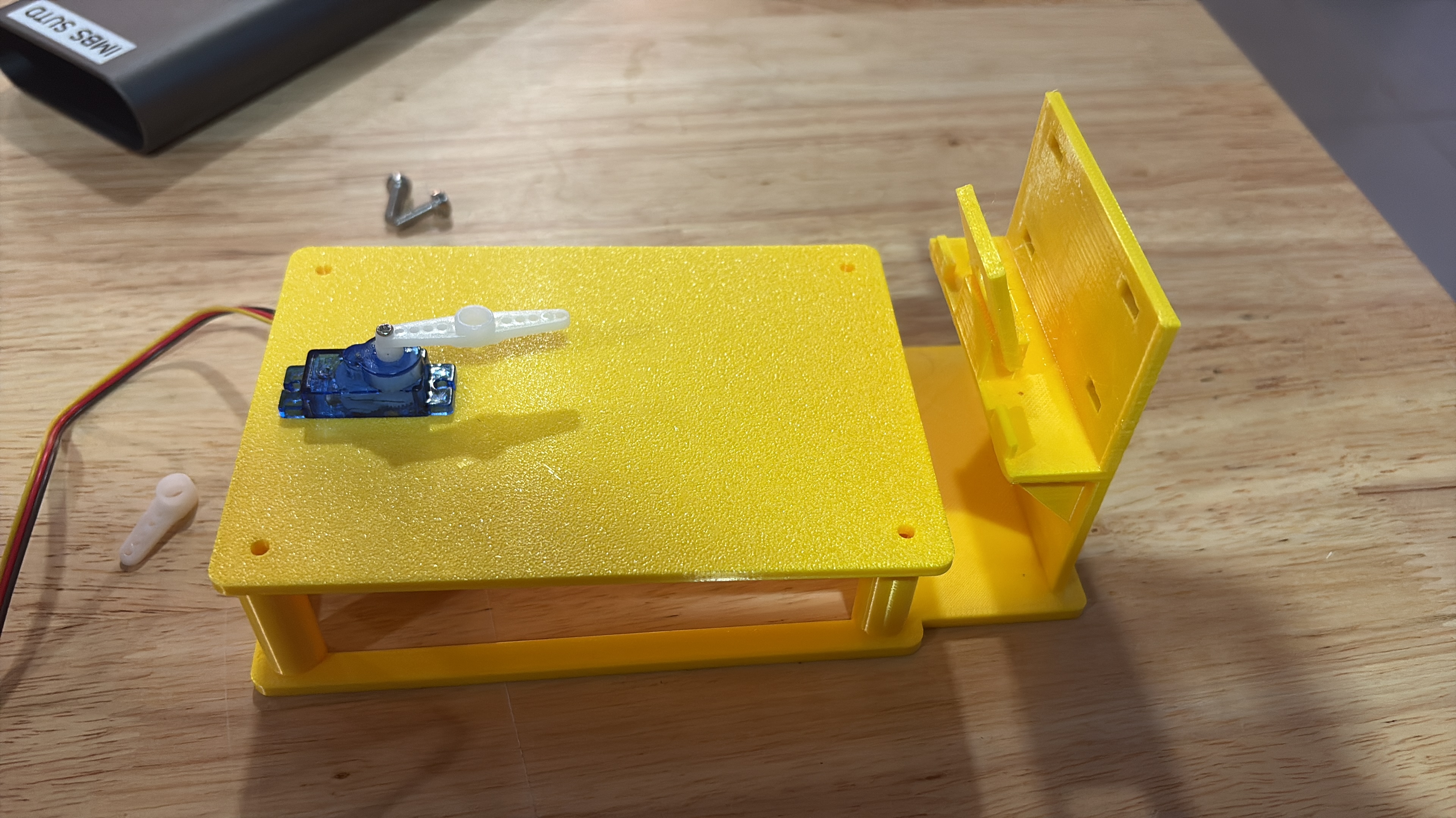Yellow 3D-printed Miltalk project platform with a blue servo motor and white arm